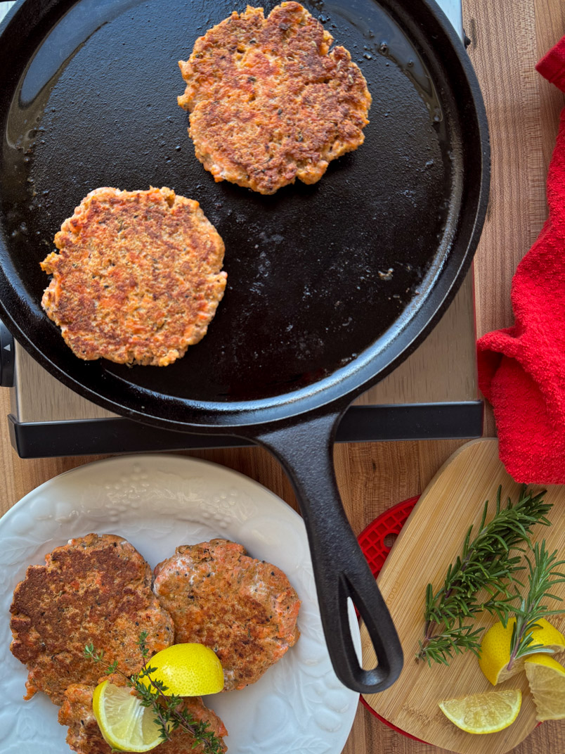 Wild salmon burger cooking on a cast-iron pan