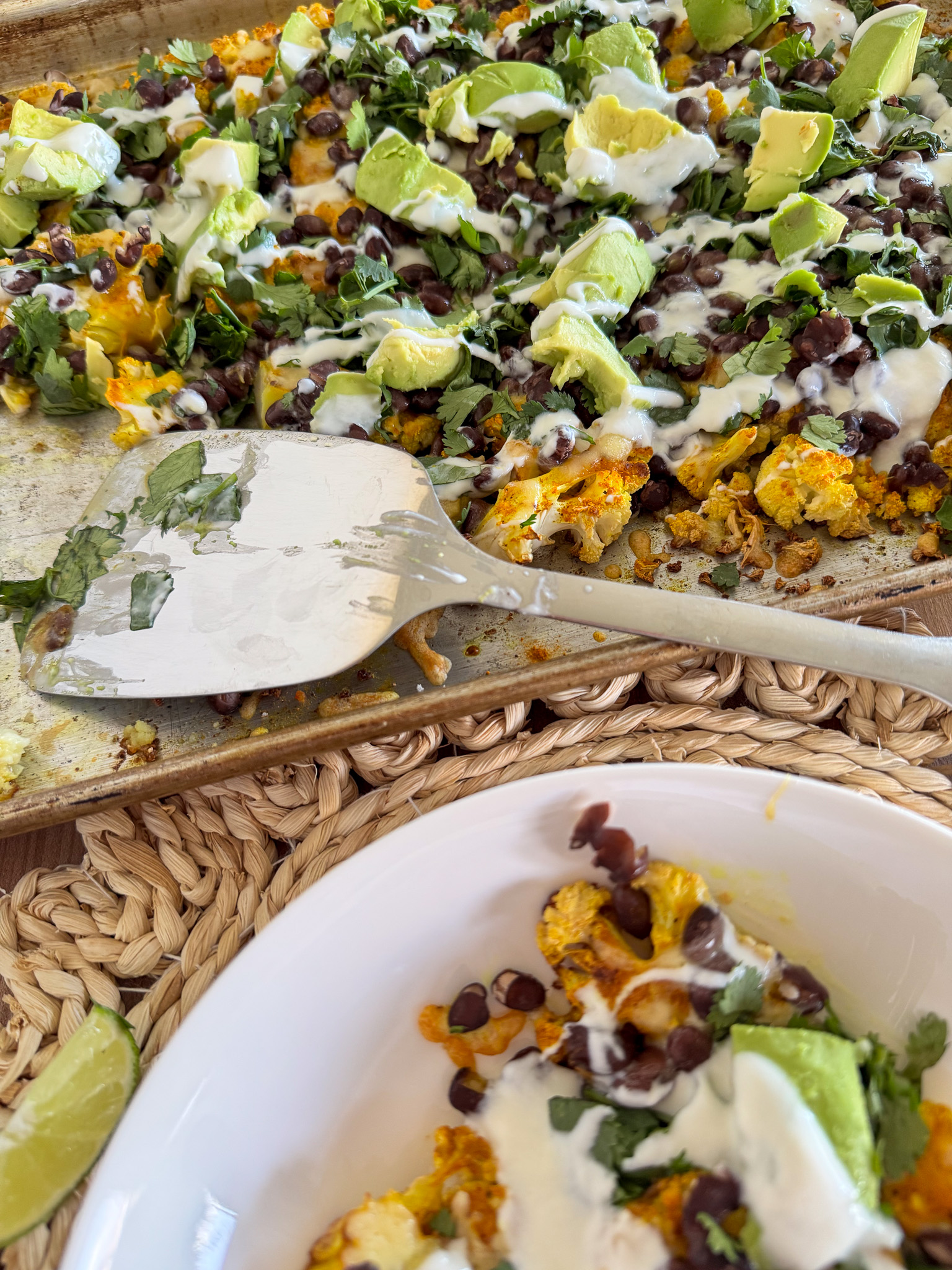 sheet pan dinner with roast cauliflower, black beans, cheese, avocado, and cilantro