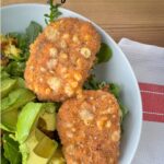 salmon fish stick with avocado on a bed of greens