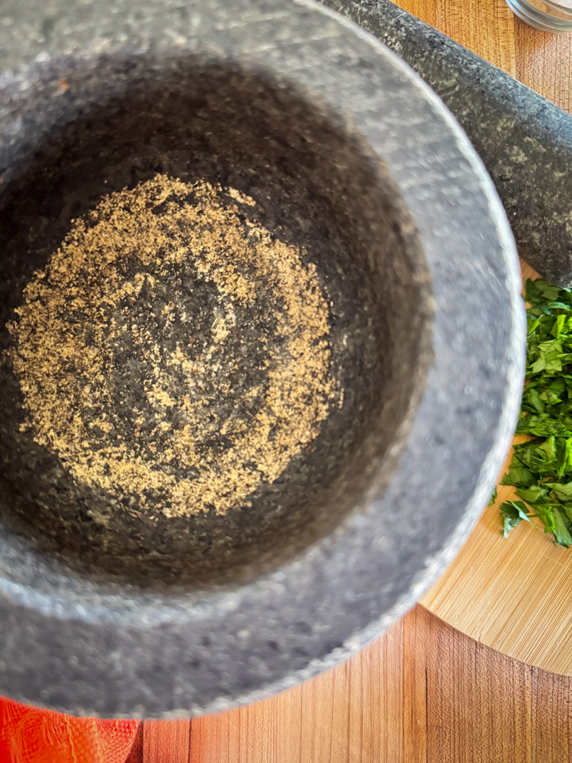 grind black peppercorns with mortar and pestle